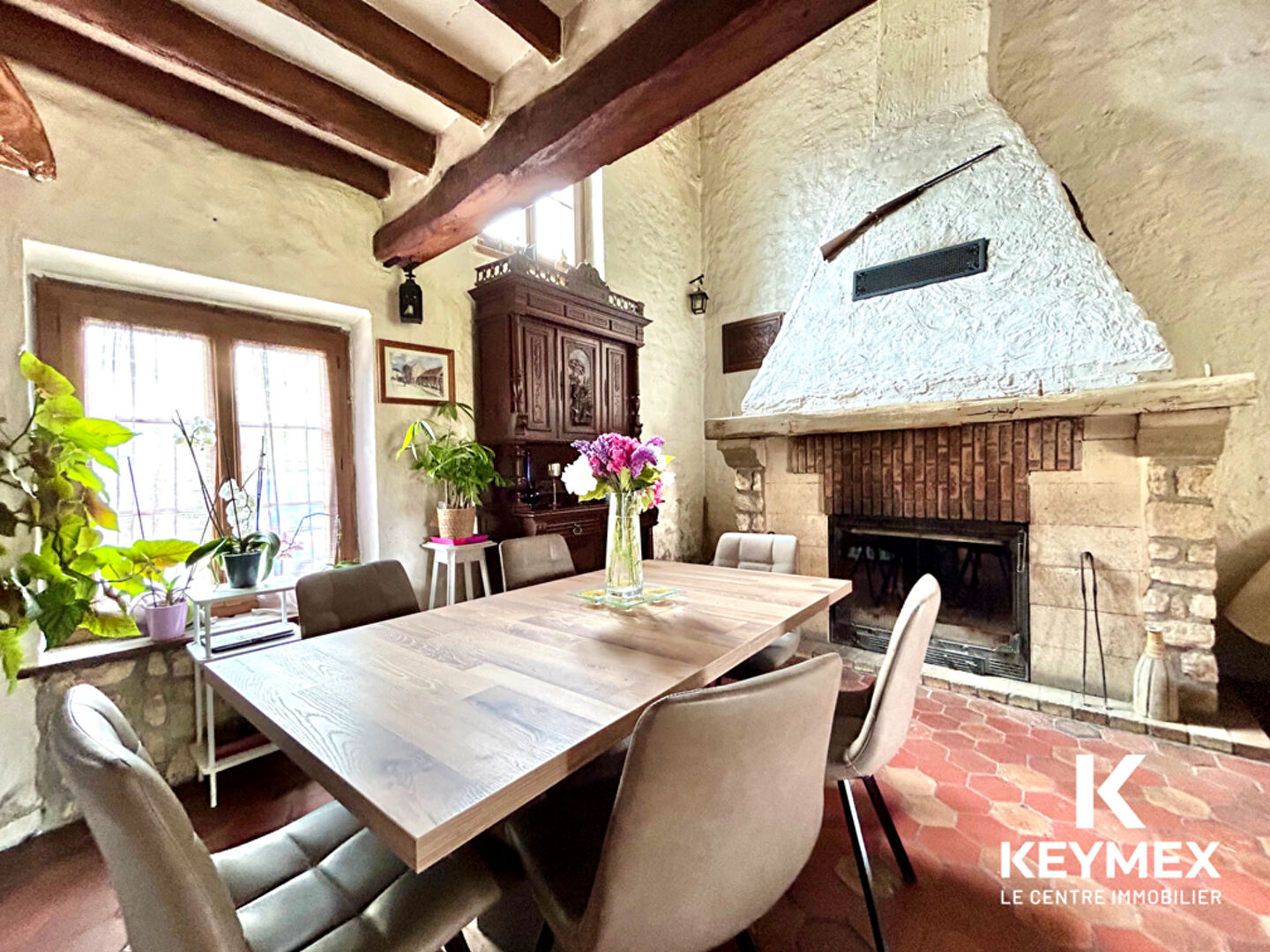 Salle à manger avec cheminée et poutres apparentes.