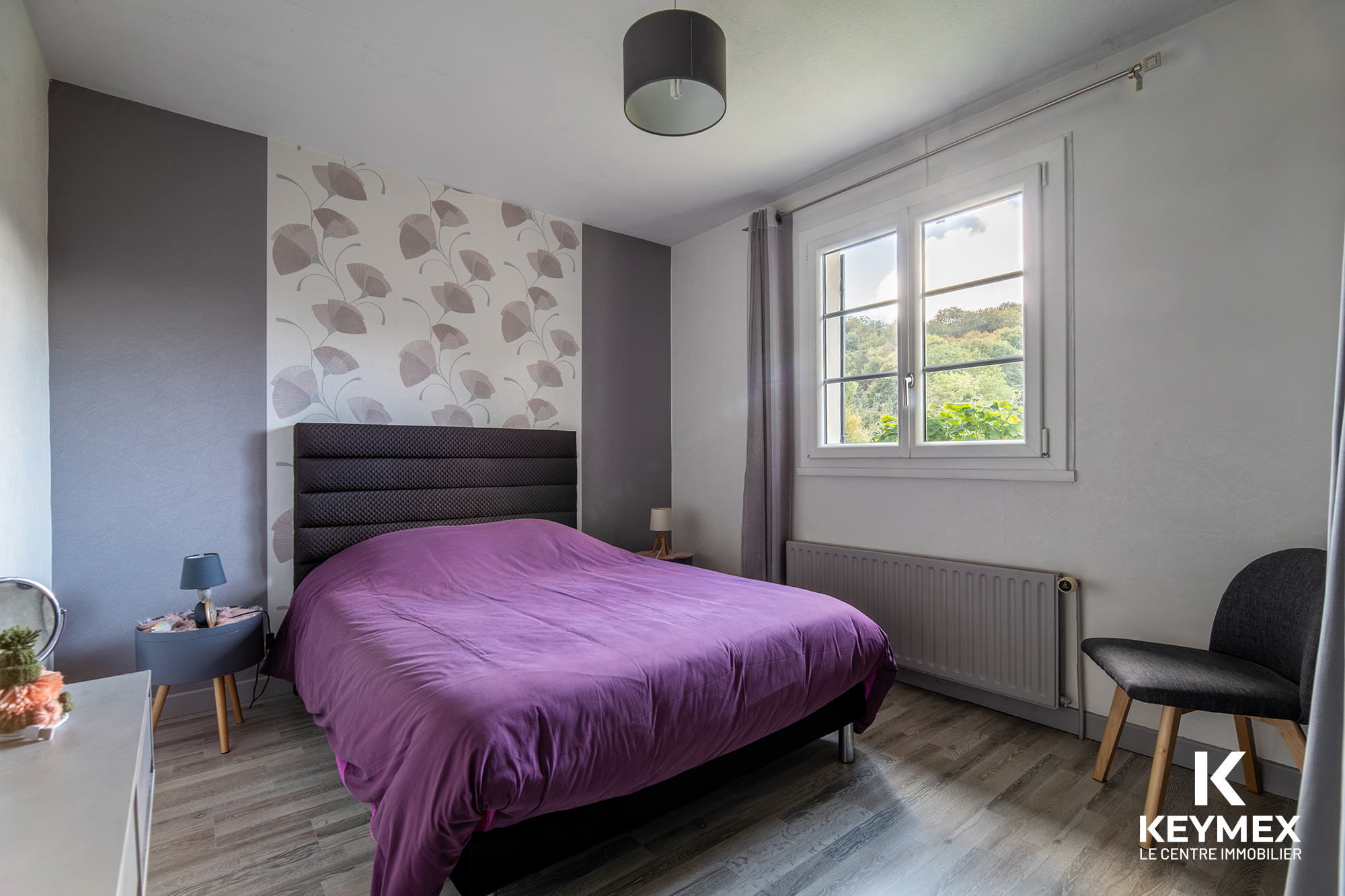 Chambre moderne avec lit violet et fenêtre lumineuse.