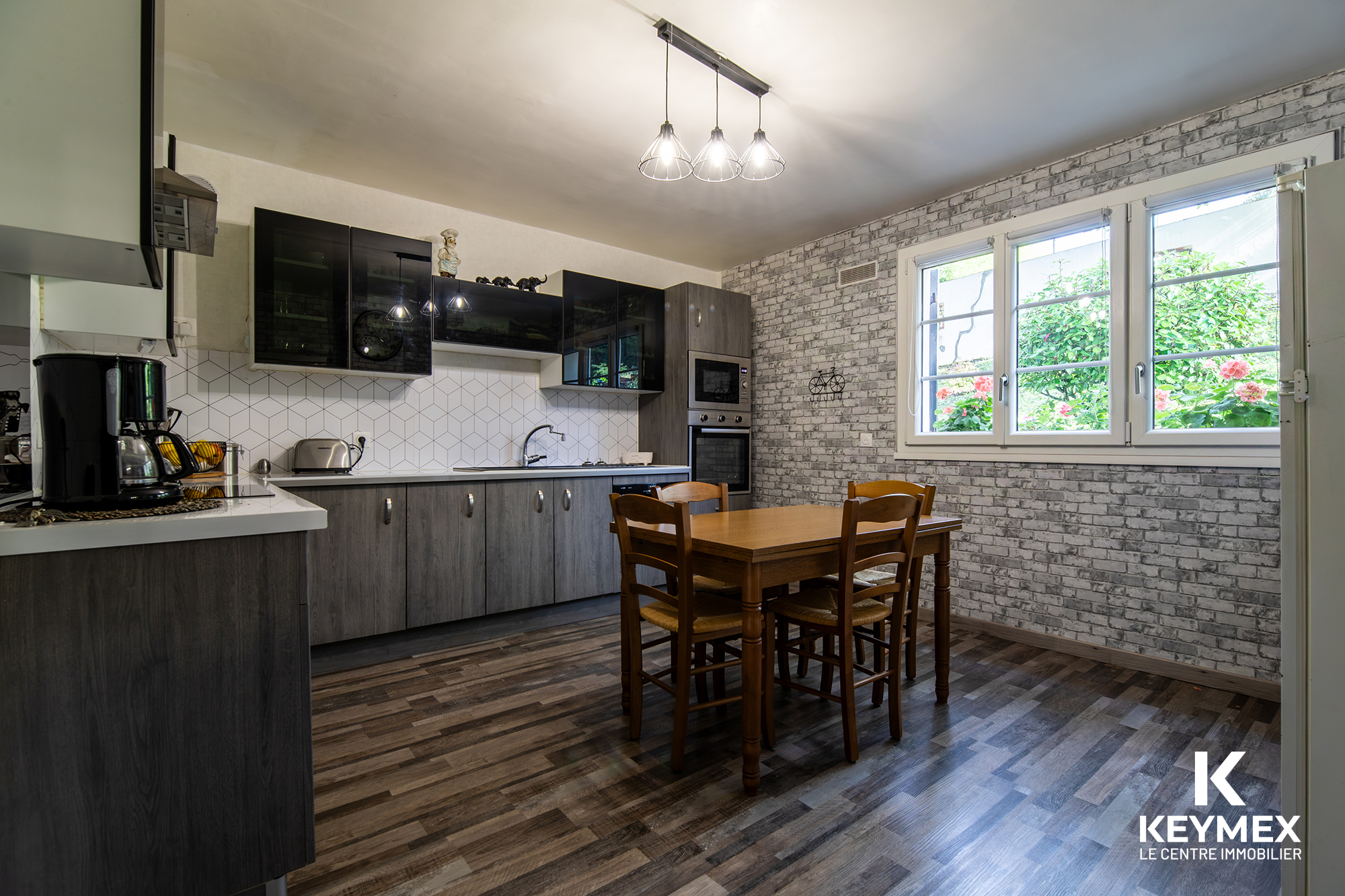 Cuisine moderne avec table en bois et fenêtres ouvertes.