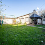 Jardin avec balançoire et barbecue en extérieur.