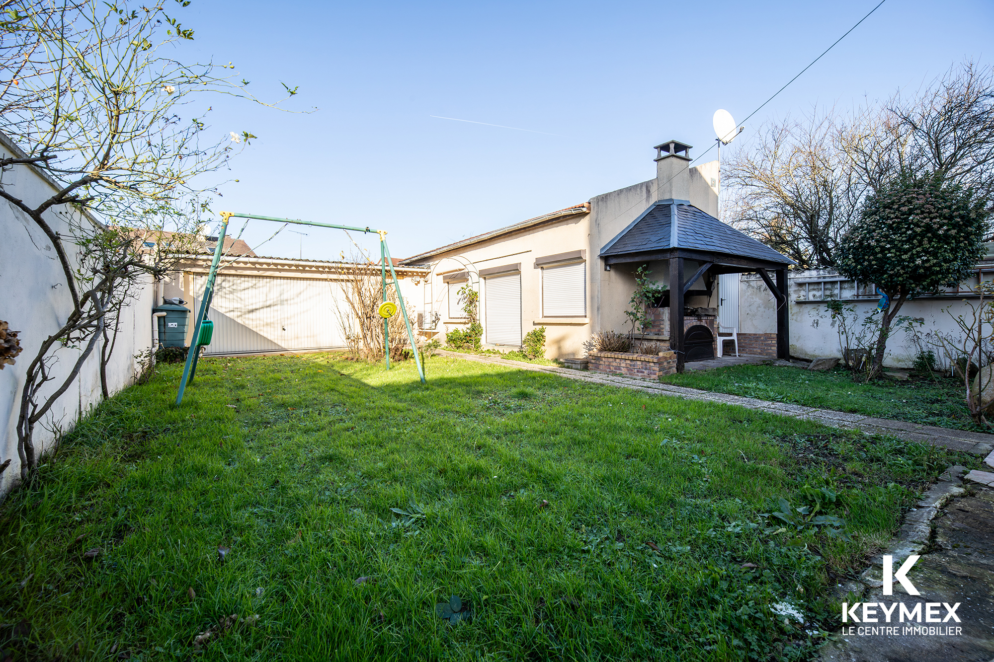 Jardin avec balançoire et barbecue en extérieur.