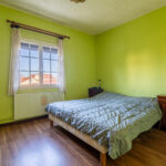 Chambre lumineuse avec murs verts et parquet bois