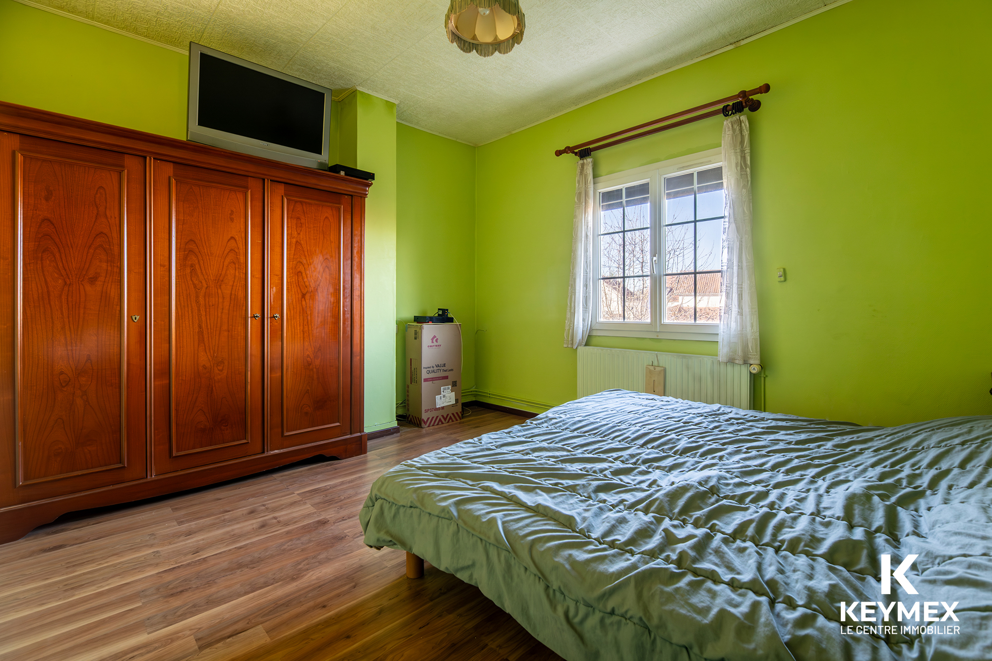 Chambre lumineuse avec armoire et télévision.