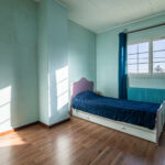 Chambre lumineuse avec lit simple et parquet bois.