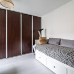 Chambre moderne avec lit et armoire en bois sombre.