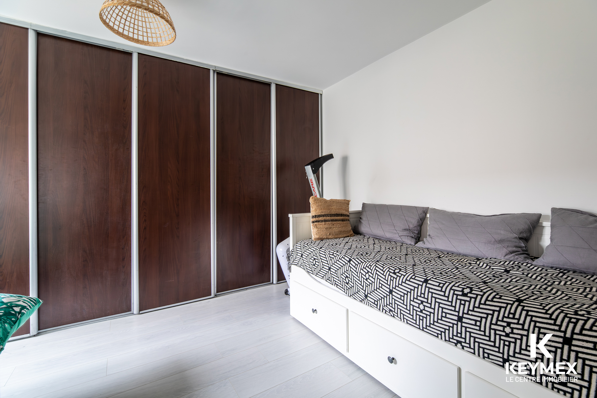 Chambre moderne avec lit et armoire en bois sombre.