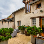 Terrasse extérieure avec plantes en pots et chaises grises.