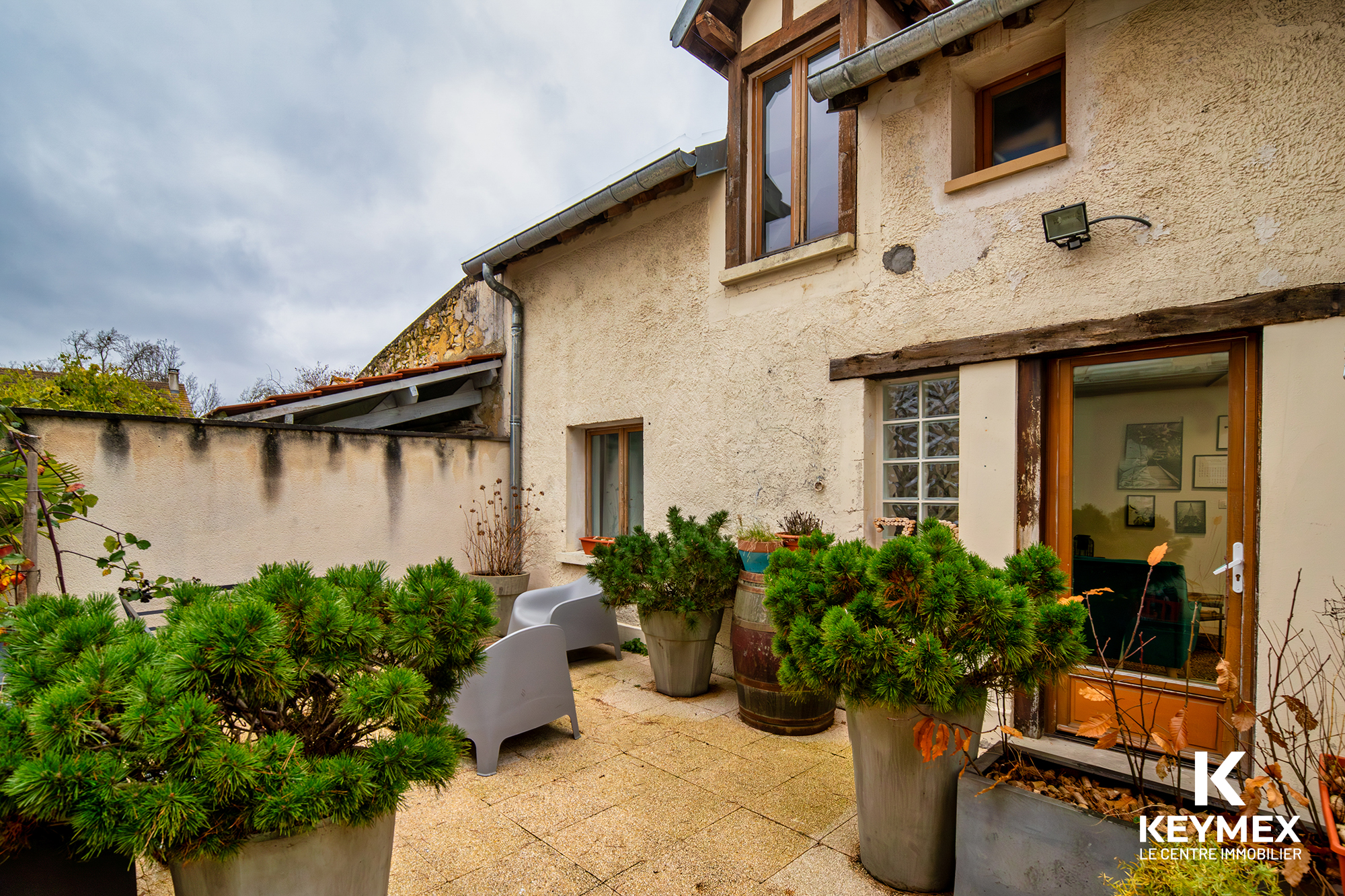 Terrasse extérieure avec plantes en pots et chaises grises.