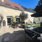 Terrasse ensoleillée avec mobilier de jardin et barbecue.