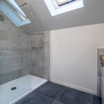 Salle de bain moderne avec douche vitrée et lavabo.