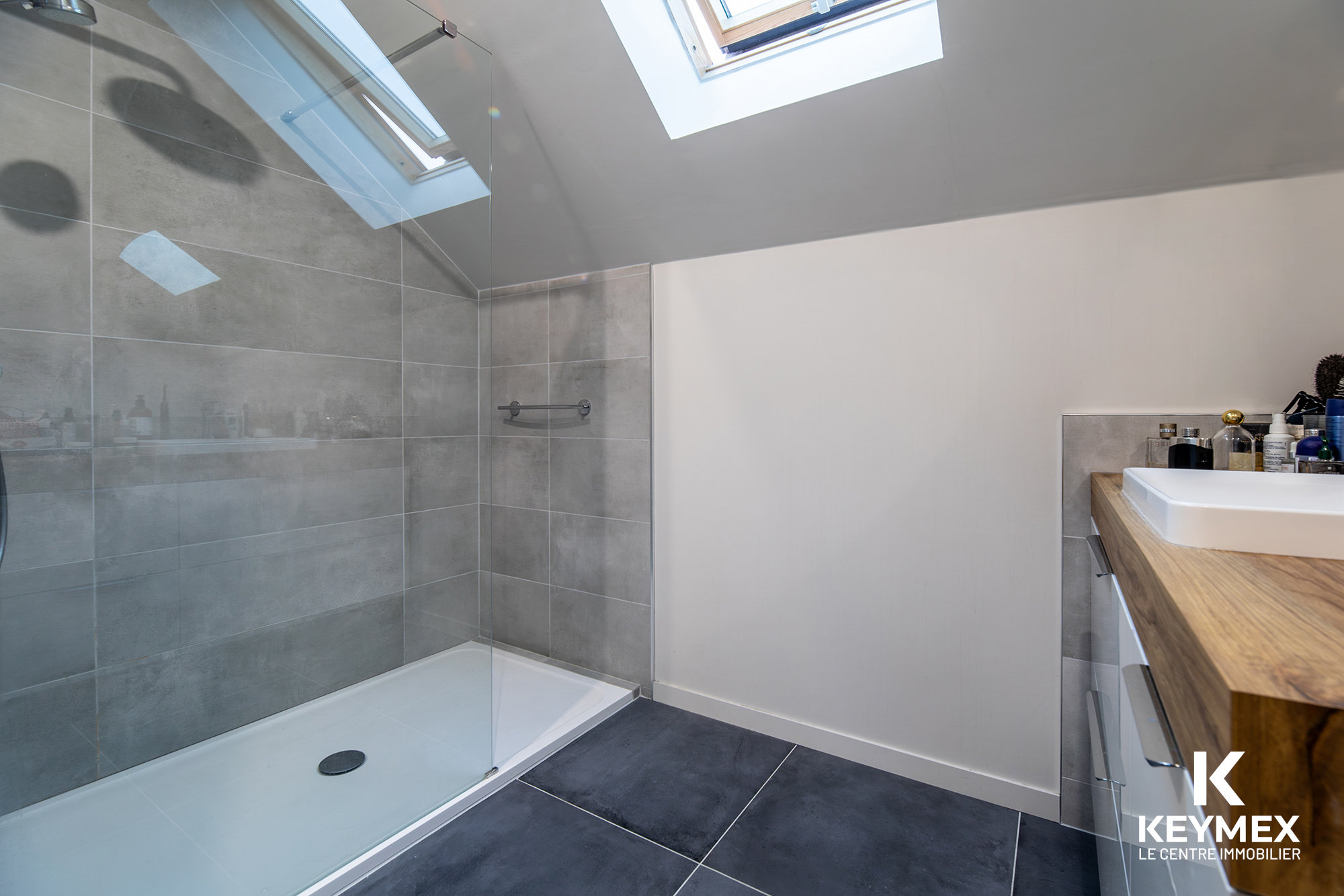 Salle de bain moderne avec douche vitrée et lavabo.