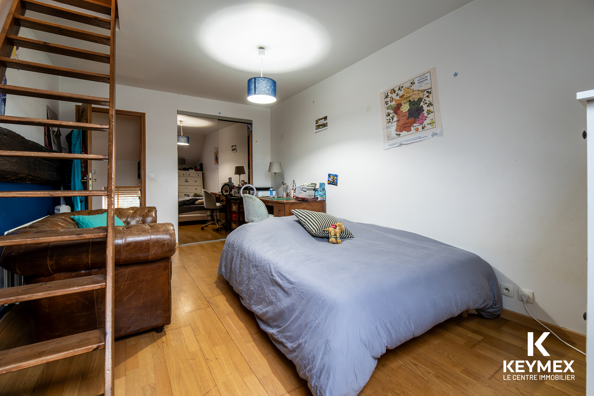 Chambre moderne avec lit, canapé et bureau.