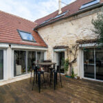 Terrasse en bois avec table et chaises noires.