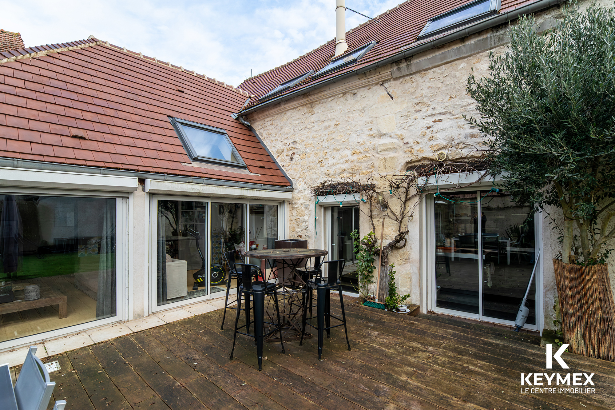 Terrasse en bois avec table et chaises noires.