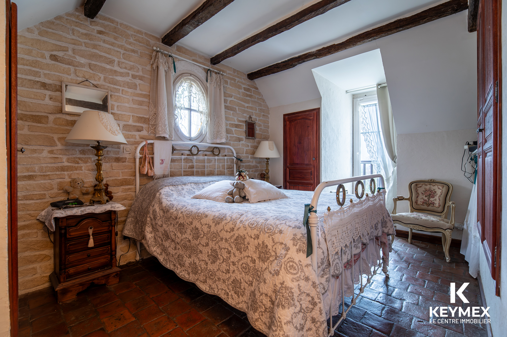 Chambre rustique avec lit en fer forgé et fenêtre.