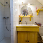 Salle de bain avec douche et lavabo jaune