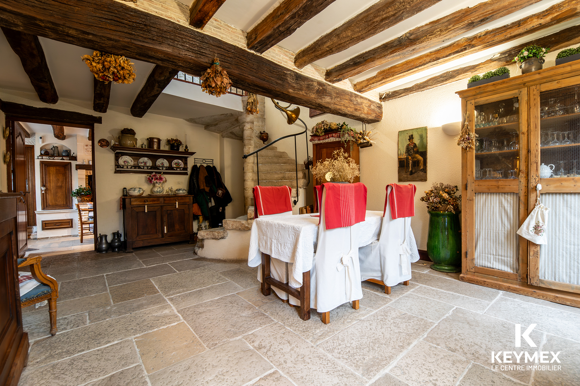 Salle à manger rustique avec poutres apparentes et décoration florale.