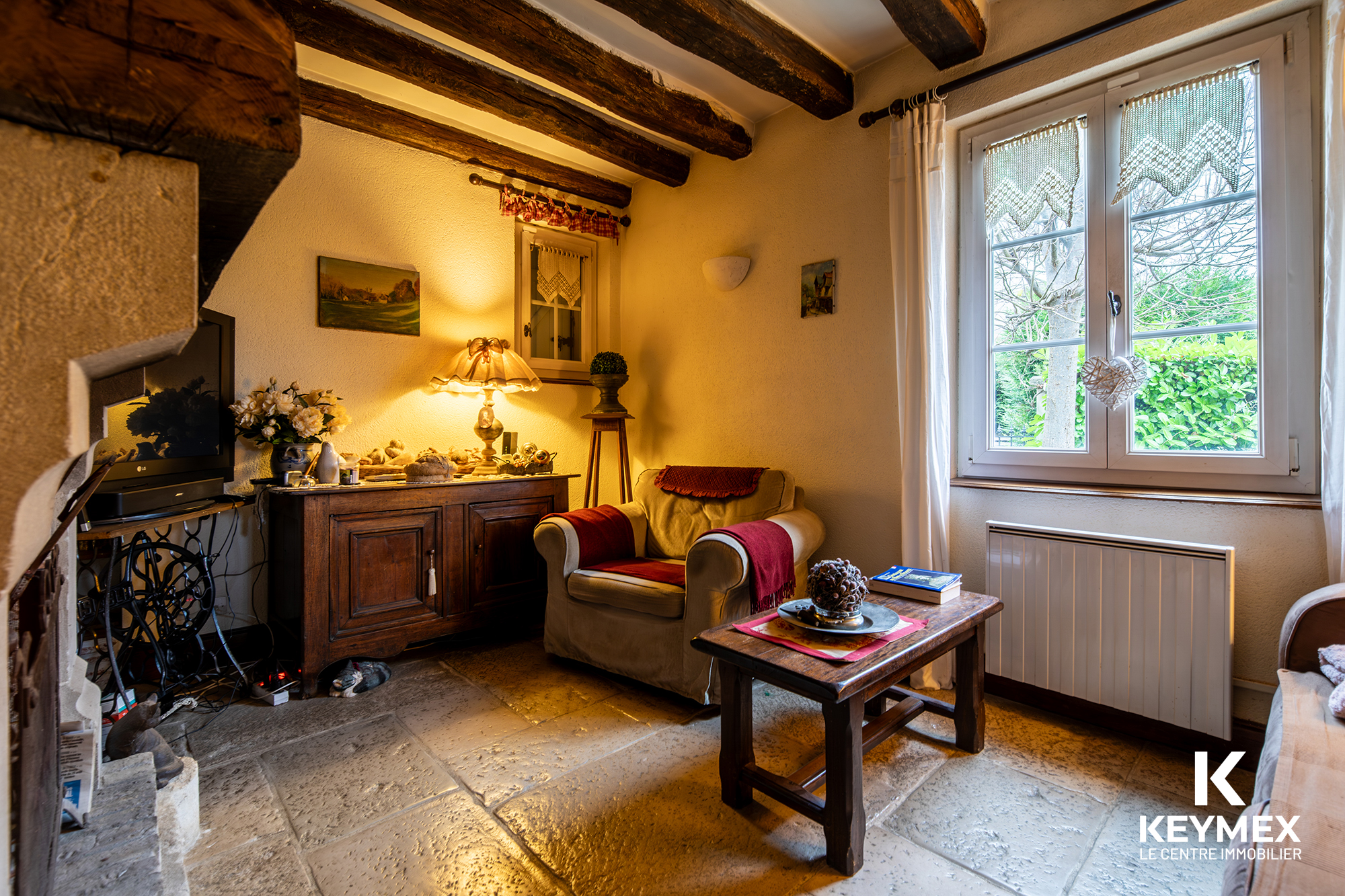 Salon rustique avec cheminée et fenêtre lumineuse.