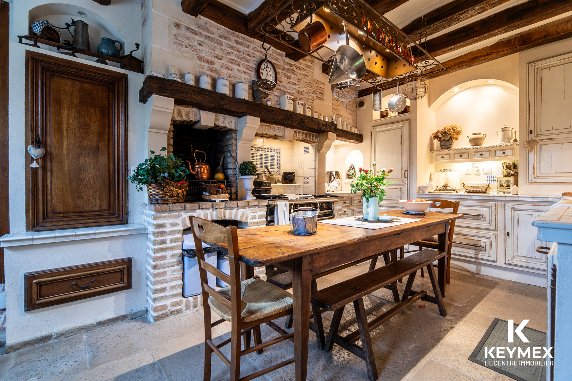 Cuisine rustique avec table en bois et cheminée.