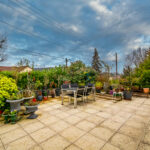 Terrasse extérieure avec plantes et mobilier de jardin.