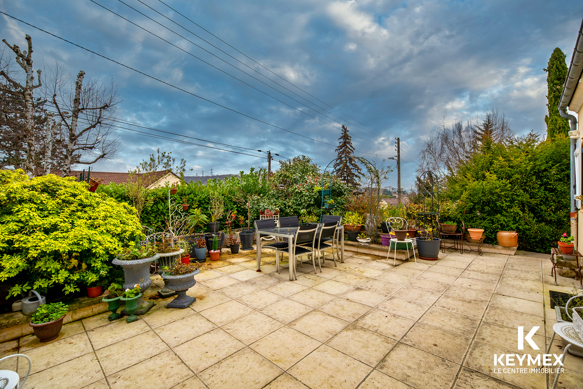 Terrasse extérieure avec plantes et mobilier de jardin.