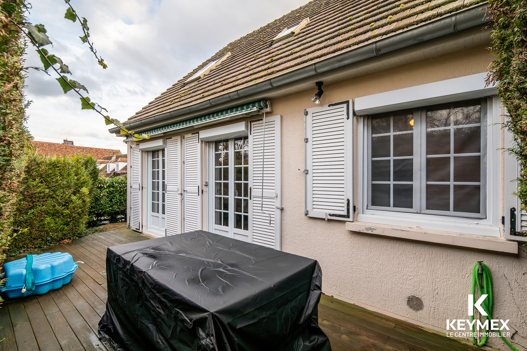 Terrasse maison avec fenêtres et volets blancs