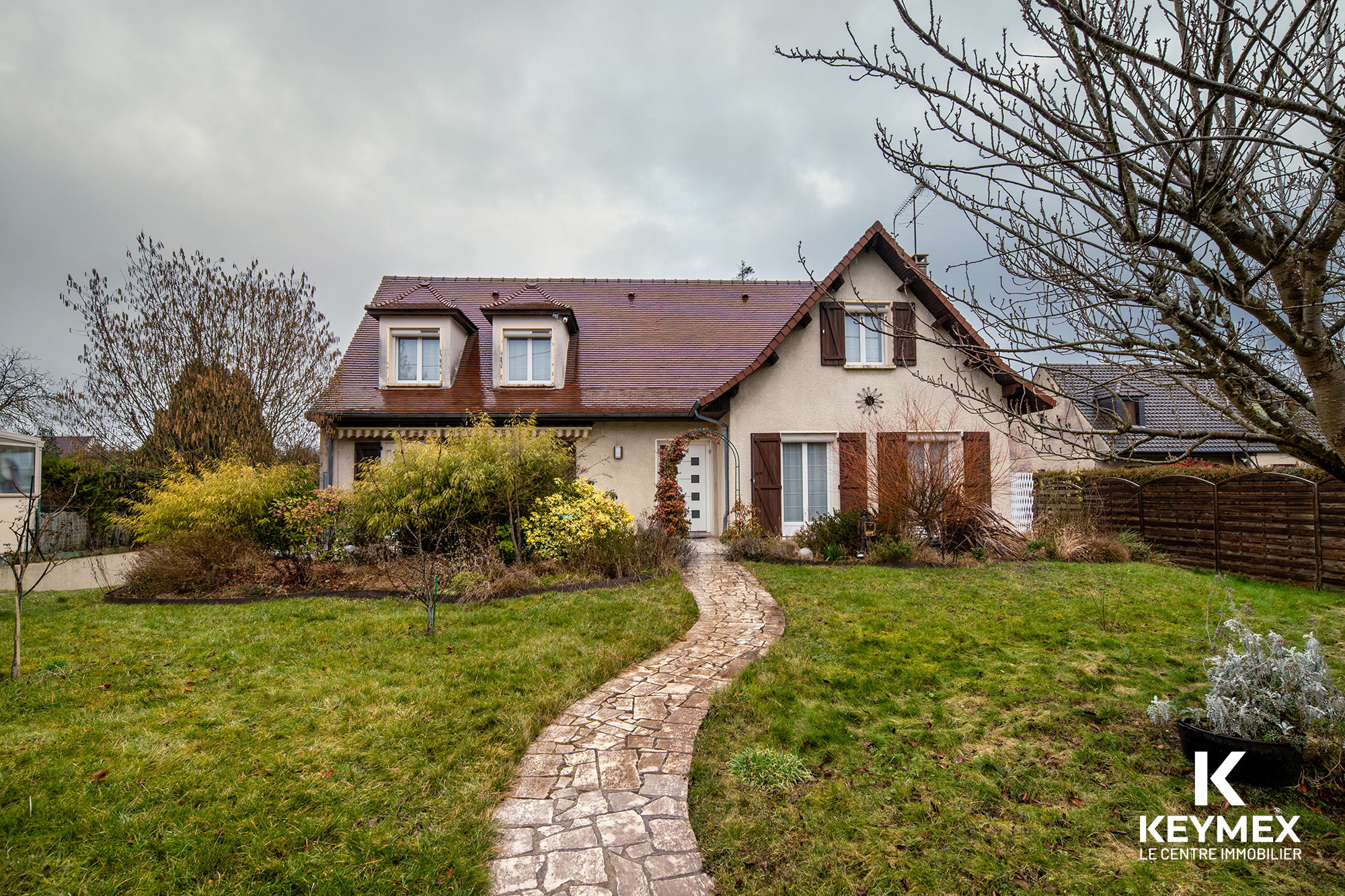 Maison avec jardin et allée en pierre.