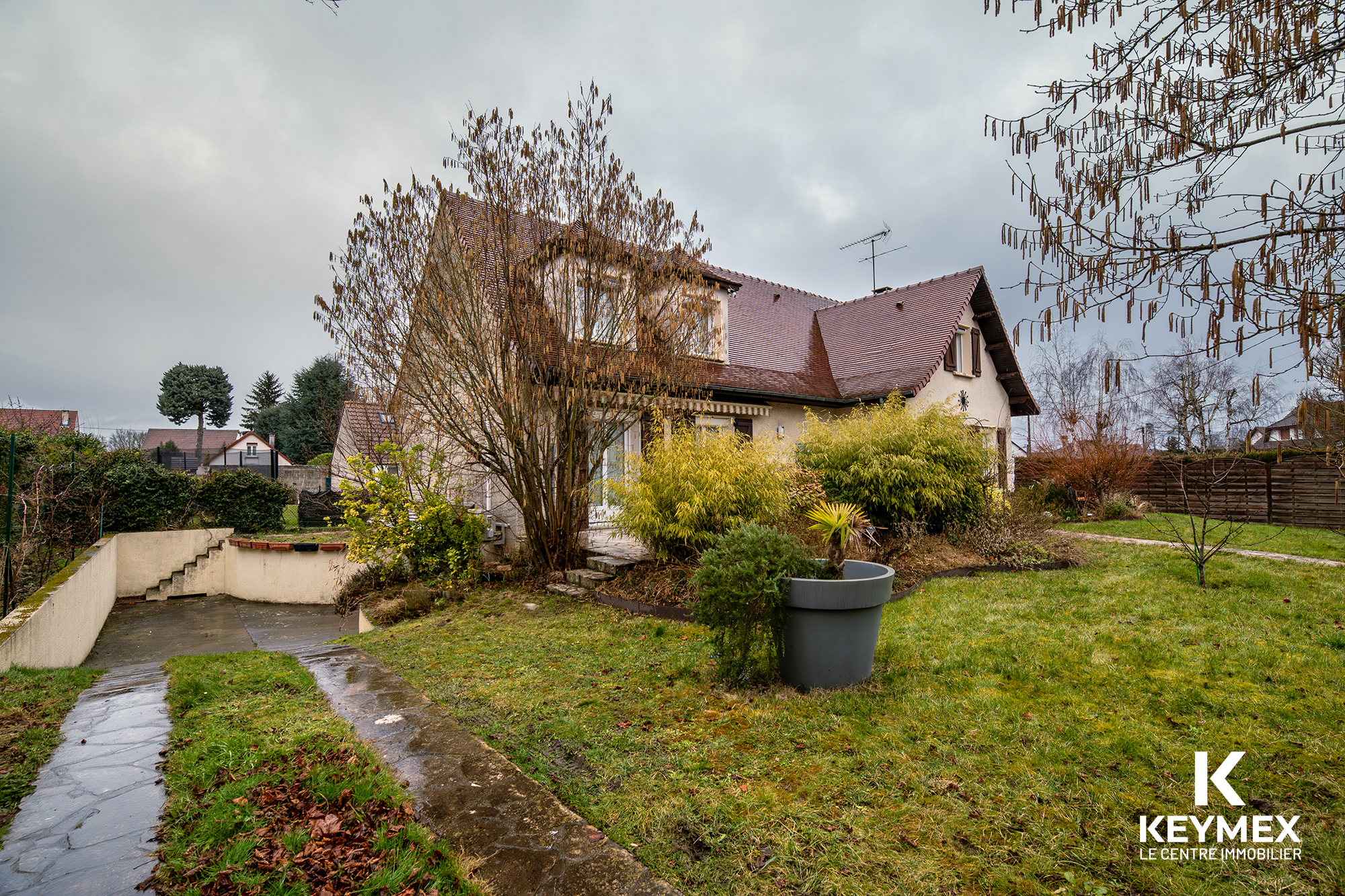 Maison avec jardin en hiver, ciel nuageux