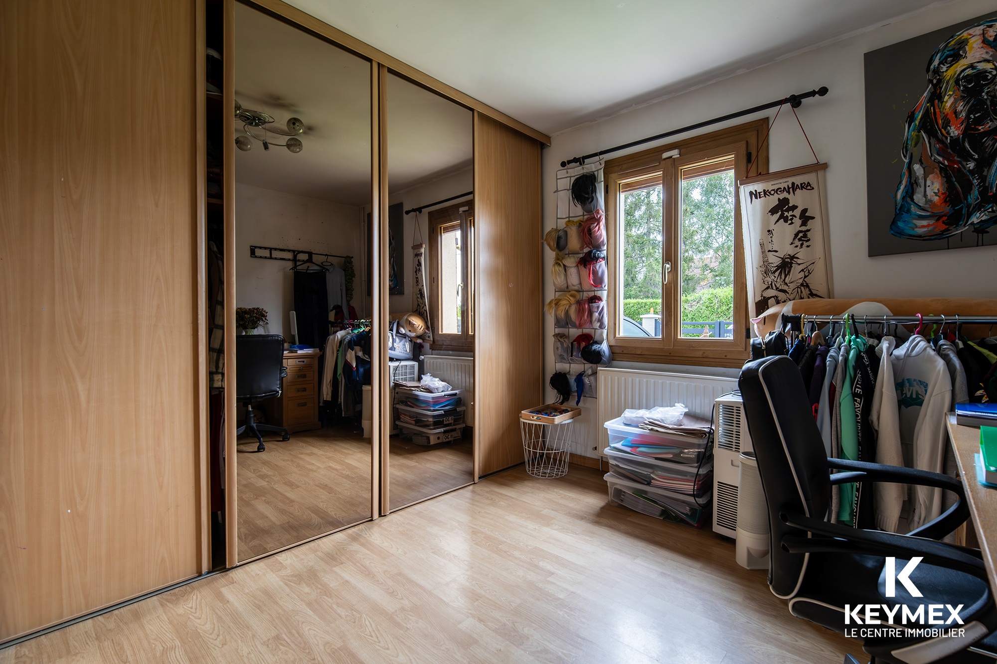 Chambre avec placards miroir et vêtements accrochés.