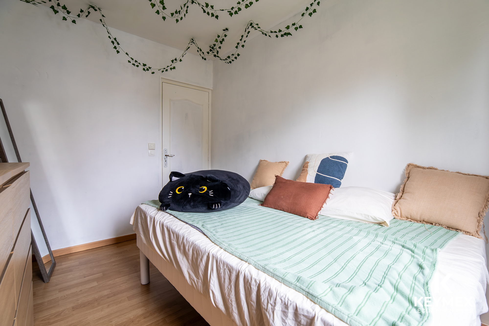 Chambre avec lit et coussin chat noir.