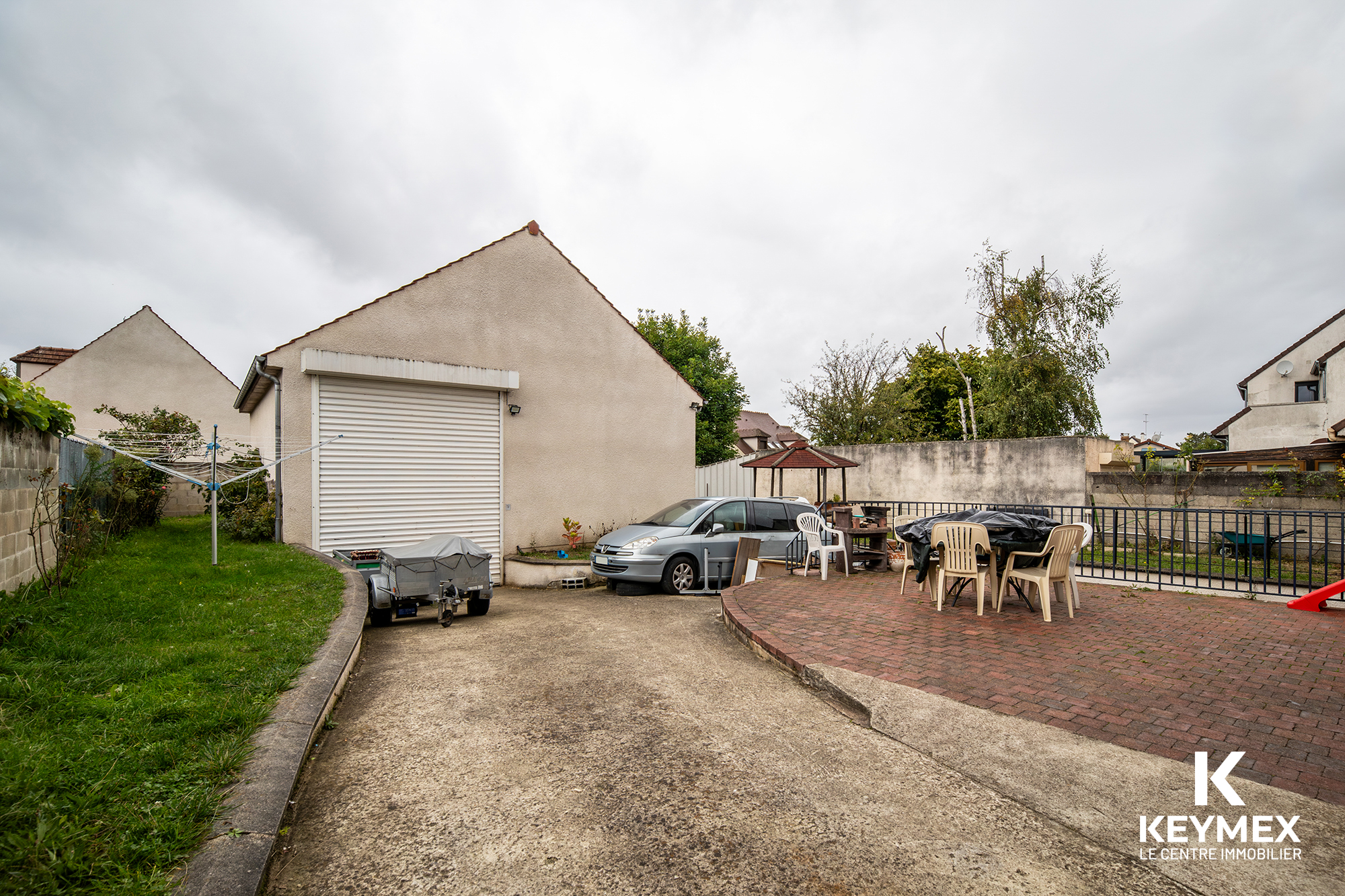 Cour extérieure avec mobilier et garage en arrière-plan.