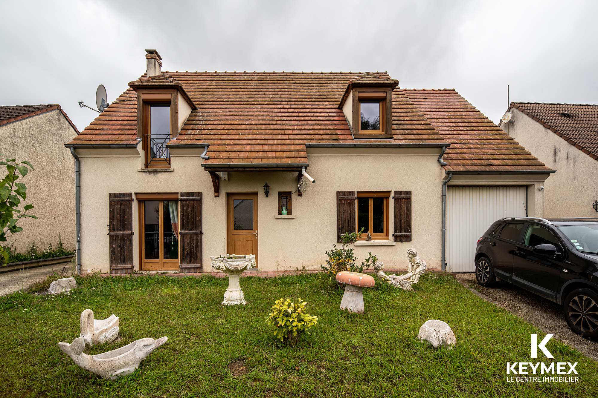 Maison avec jardin devant et voiture garée