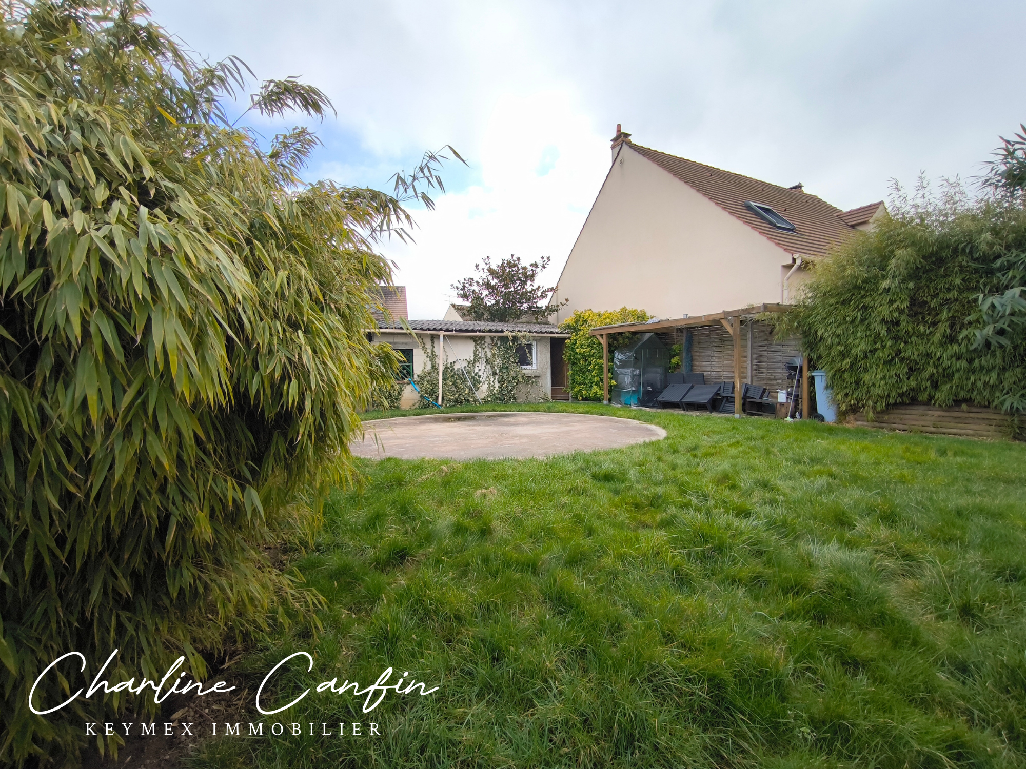 Jardin arrière avec cabane et verdure luxuriante.