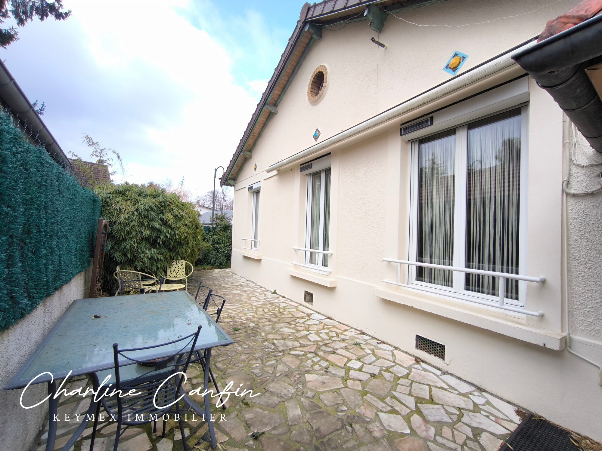 Maison avec terrasse et mobilier de jardin.