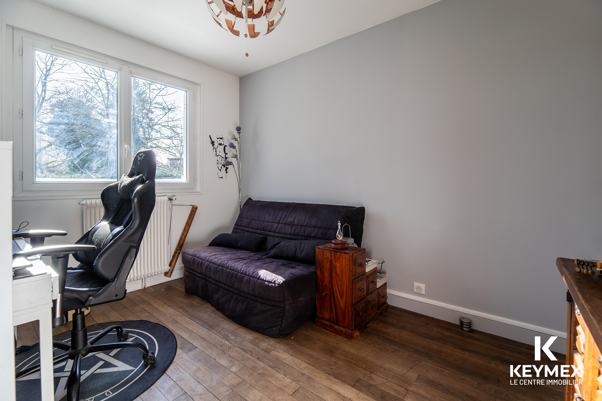 Bureau avec chaise et canapé devant fenêtre.