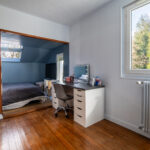 Chambre avec bureau, lit et fenêtres lumineuses.