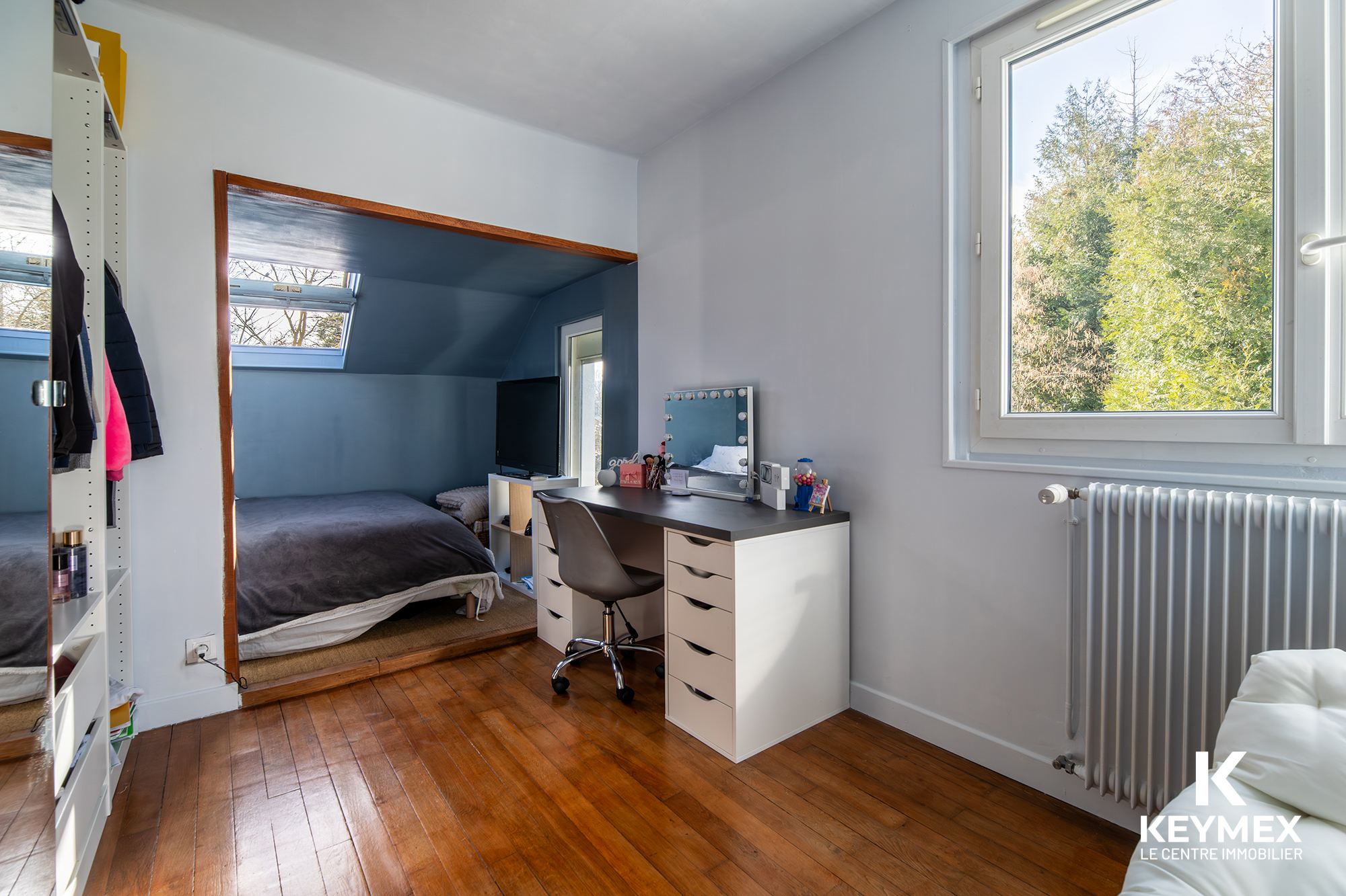 Chambre avec bureau, lit et fenêtres lumineuses.