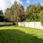 Jardin avec arbres et clôture en béton