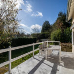 Terrasse ensoleillée avec table et chaises blanches.