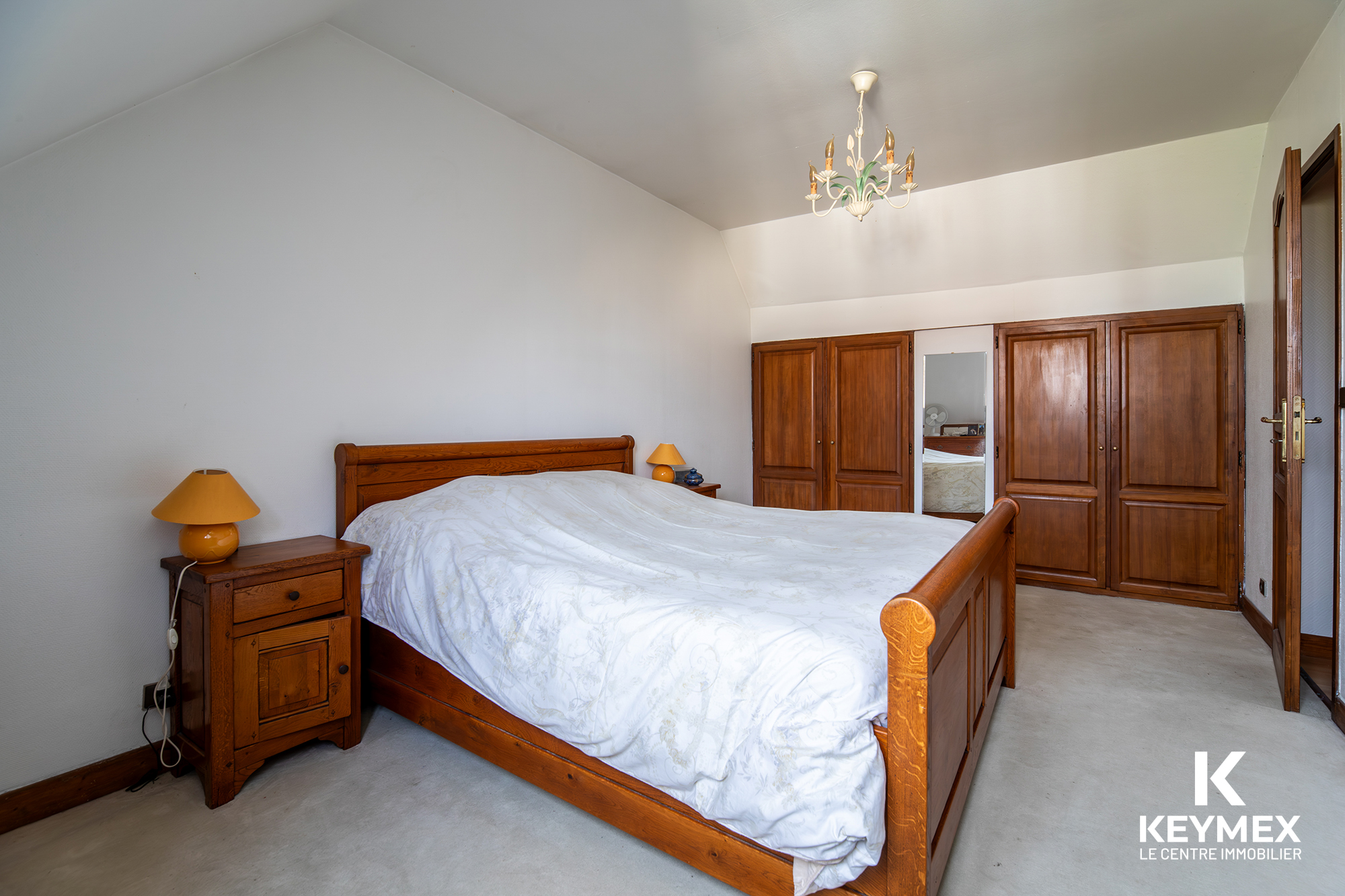 Chambre spacieuse avec lit double et armoire bois.