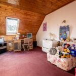 Chambre enfant mansardée avec jouets et bureau.