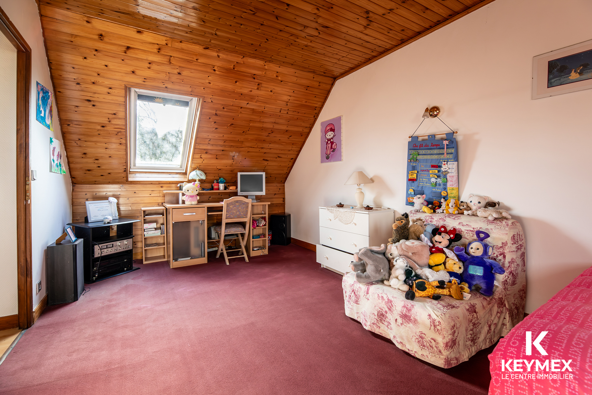 Chambre enfant mansardée avec jouets et bureau.