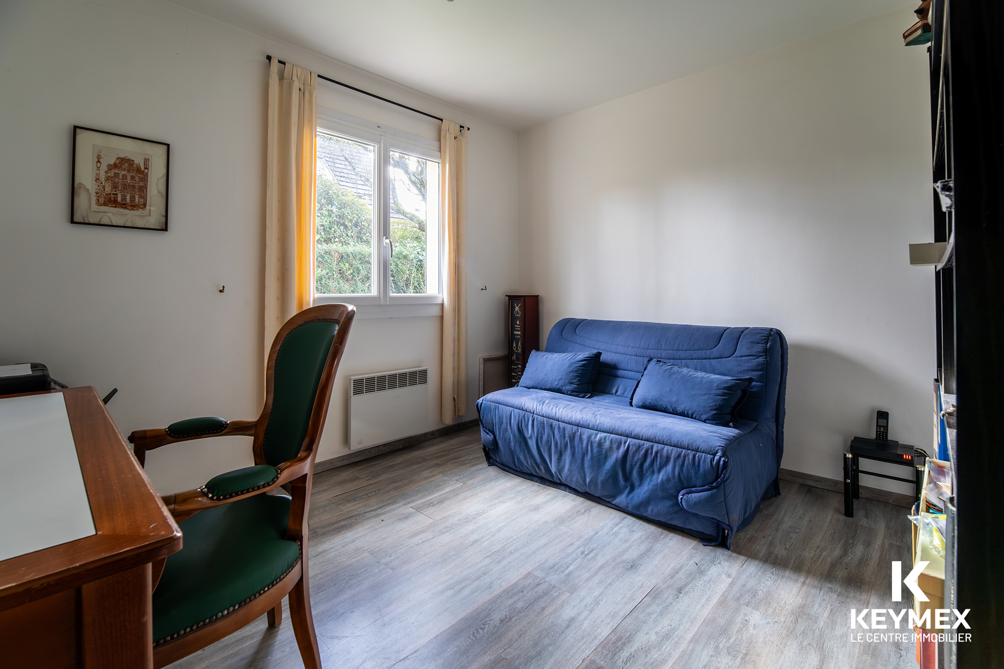 Salon avec canapé bleu et fauteuil en bois.