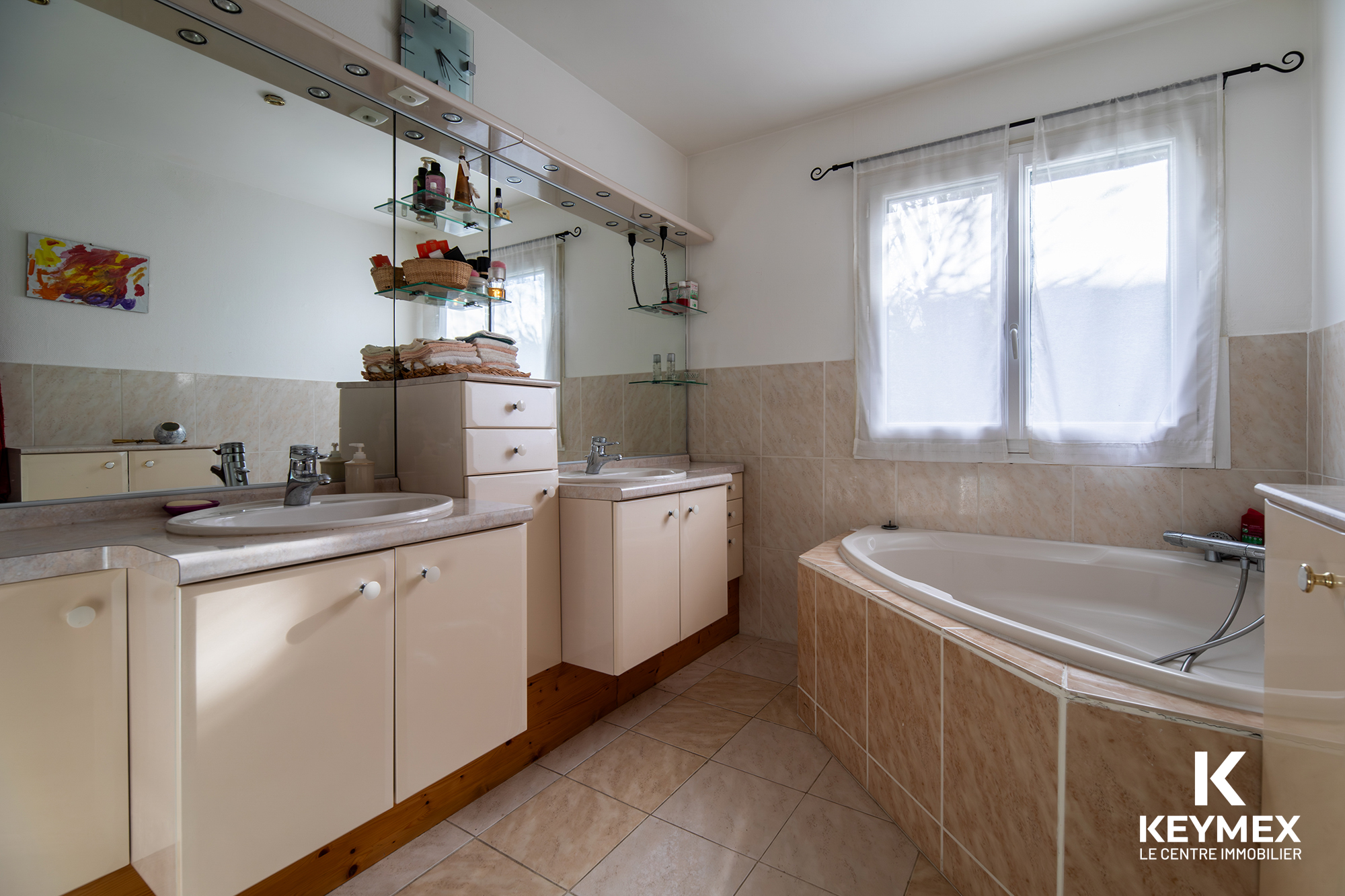 Salle de bain lumineuse avec grande baignoire et miroir.