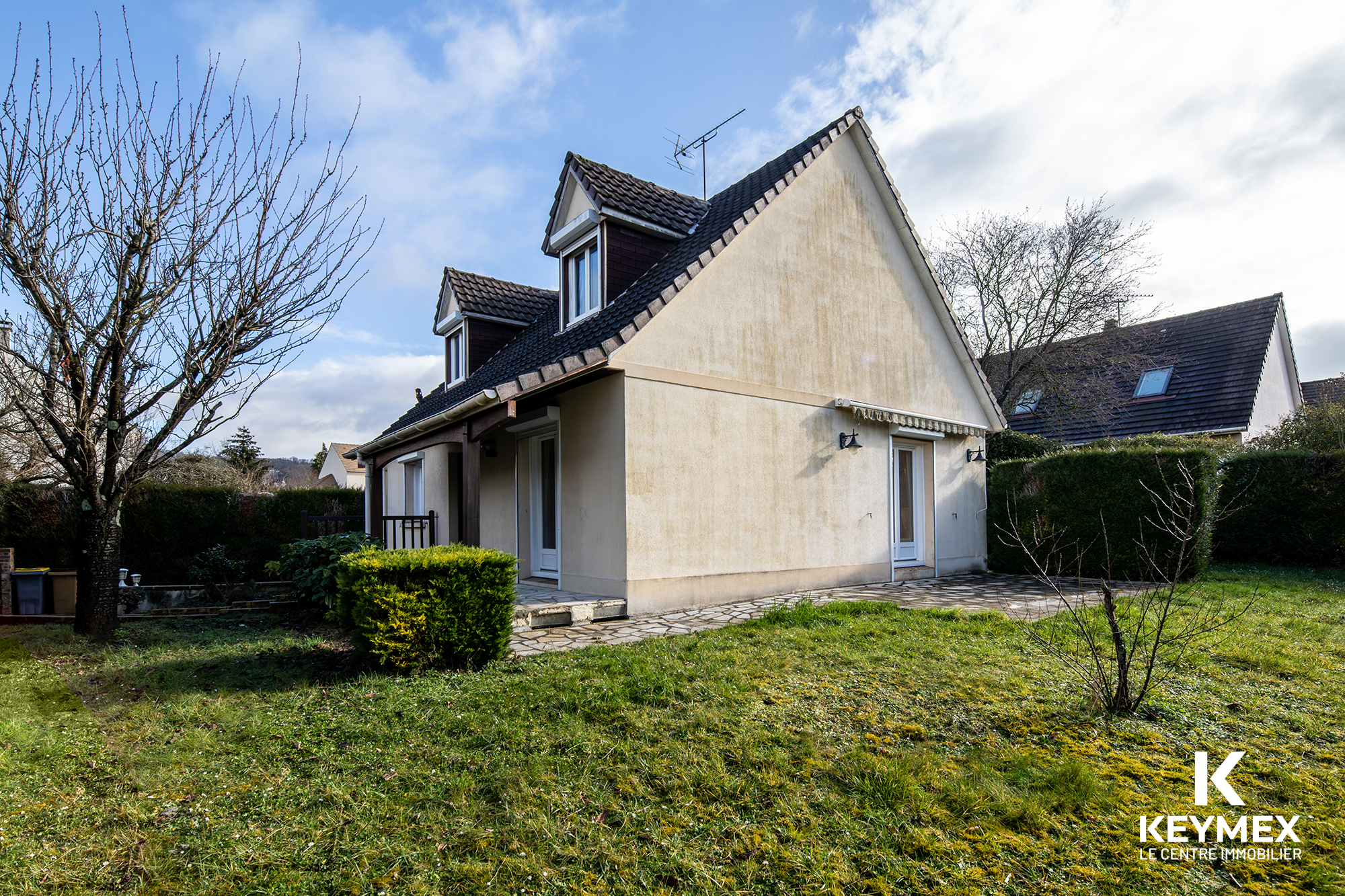 Maison avec jardin et terrasse ensoleillée.