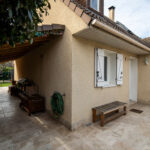 Entrée de maison avec abri et jardin verdoyant.