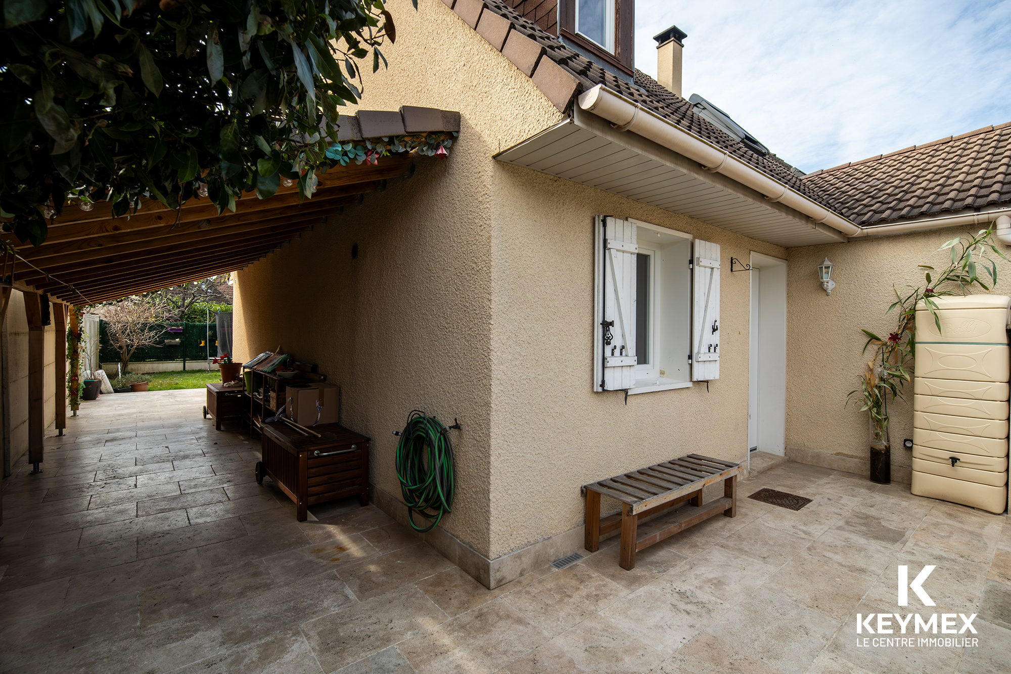 Entrée de maison avec abri et jardin verdoyant.