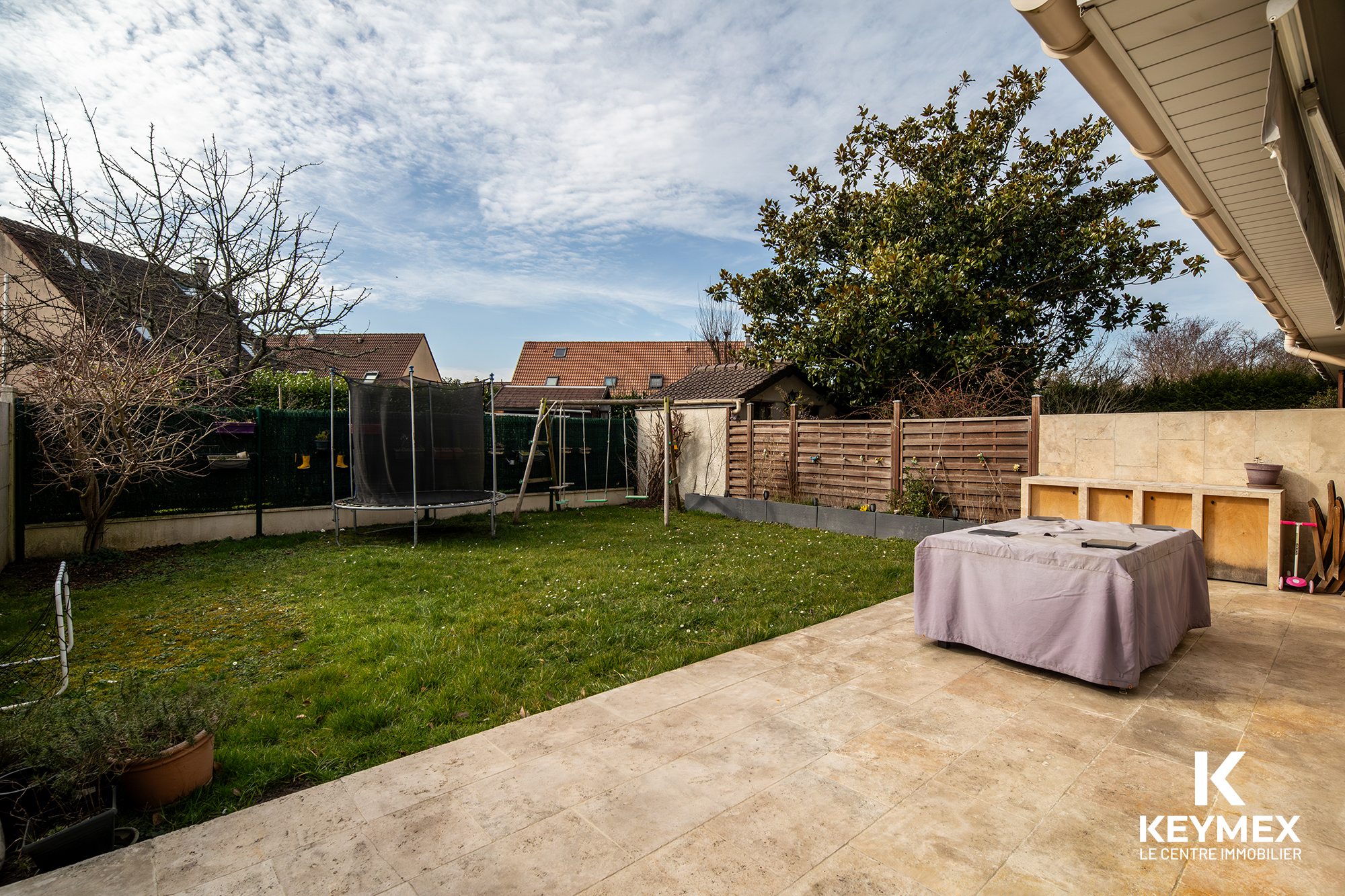 Jardin avec trampoline et terrasse pavée