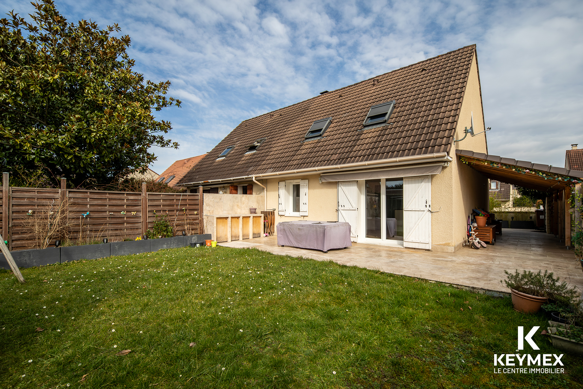 Maison avec jardin et terrasse, ciel dégagé.