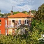 Maison en brique avec jardin verdoyant.